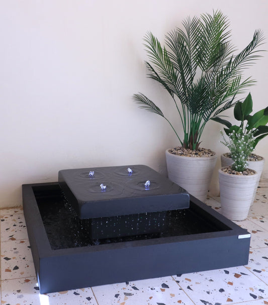 نافورة ماء سوداء مع أحجار زخرفية على خلفية جدار أبيض