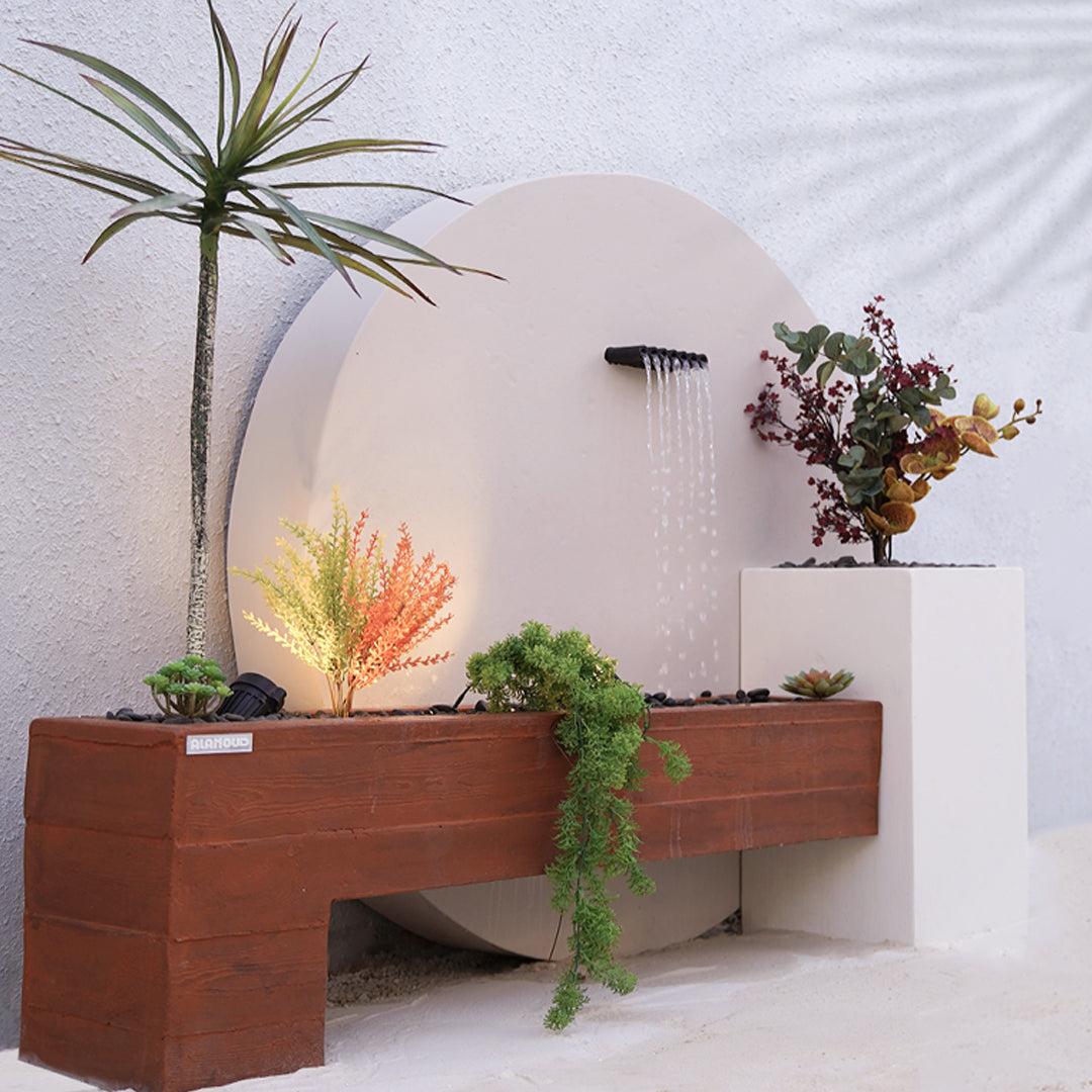 شلال داخلي مميز مصنوع من الكونكريت مع إضاءة ونباتات طبيعية حوله.