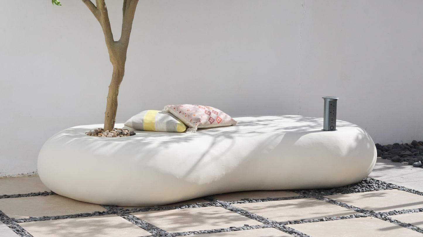 كرسي نيست خارجي  بلون أوف وايت مع شجرة مزروعة ووسائد جلوس، مزود بتوصيلة كهربائية وسماعة مدمجة في فناء حديقة.
