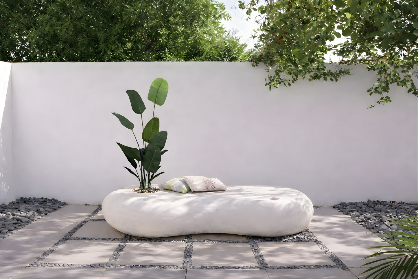 كرسي خارجي عضوي بلون أوف وايت مع شجرة مزروعة ووسائد جلوس في فناء حديقة.